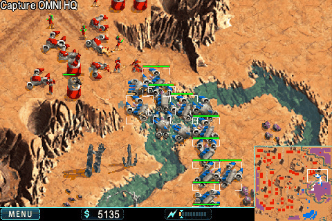 Warfare Incorporated: red and blue armour columns meeting across a desert riverbed under the objective Capture OMNI HQ, with funds and the minimap on the HUD